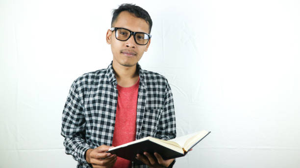 istock Handsome Asian student smiling and holding and reading book in hand 1533957045