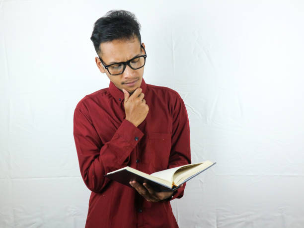 istock Portrait of Asian man holding book with thinking face expression 1533960803