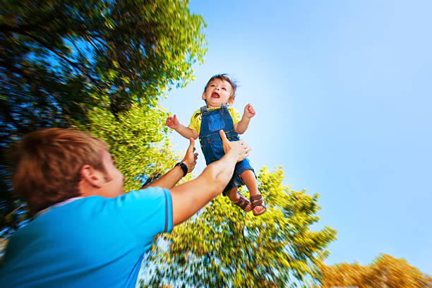 istock happy daddy is throwing  baby in a greenl summer park 153397737