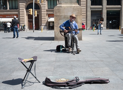 Barcelona, Spain – May 13, 2023: older man playing the guitar in the street