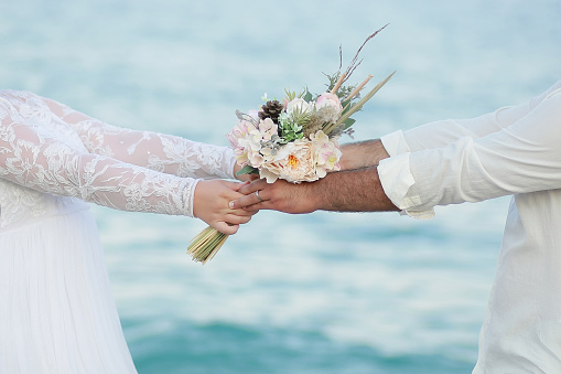 The bride and groom are holding hands and holding a bouquet of flowers.
