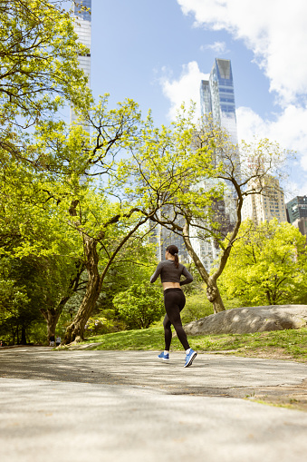 Determined Young Female Runner in Central Park, NYC. \nFun Fact: Central Park offers 58 miles of pathways and trails.