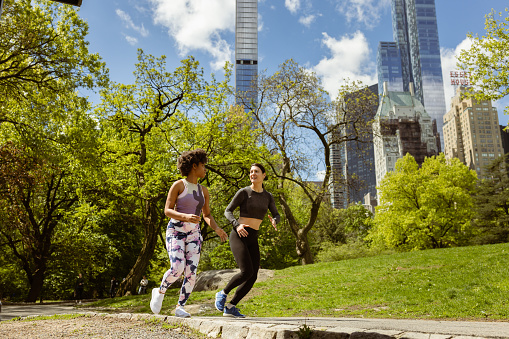Two fitness enthusiasts dash through Central Park, NYC, with the iconic high-rise skyline serving as their breathtaking backdrop. 
Fun Fact: Central Park is home to over 26,000 trees, making it a haven of greenery in the heart of the bustling city?