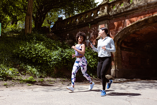 These two active women share a moment of joy as they jog through Central Park, NYC, marveling at the breathtaking skyline that complements their invigorating run. 
Fun Fact: Central Park's Great Lawn, spanning 55 acres, is one of the largest open lawns in the city and hosts numerous events, concerts, and picnics!