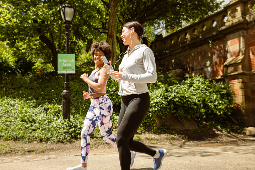 These two active women share a moment of joy as they jog through Central Park, NYC, marveling at the breathtaking skyline that complements their invigorating run. 
Fun Fact: Central Park's Great Lawn, spanning 55 acres, is one of the largest open lawns in the city and hosts numerous events, concerts, and picnics!