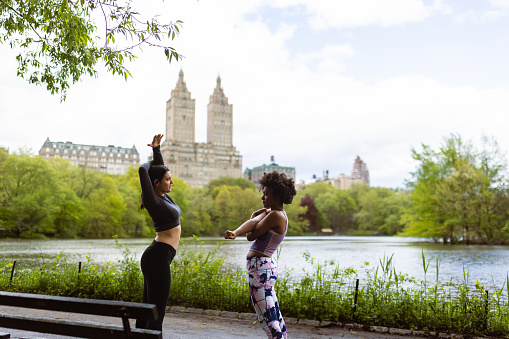 Against the breathtaking backdrop of NYC's high-rise skyline, two friends, prepare for their jog through Central Park. \nFun Fact: Central Park's vast 843 acres make it larger than the principality of Monaco!