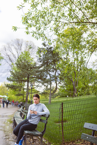 Woman texting after finishing jogging in Central Park