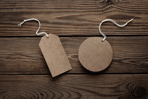 Empty rectangular and round craft price tags with string on wooden background. Template for design
