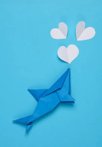 Photo of Origami shark with hearts on a blue background. Love concept