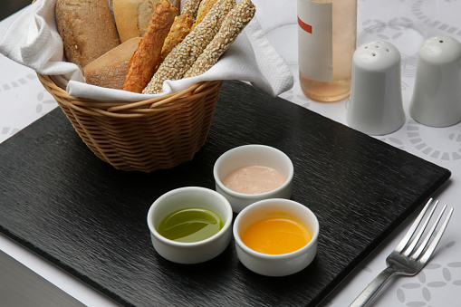 Different sauces and dips in bowls on the restaurant tableDifferent sauces and dips in bowls served with breadsticks on the restaurant table