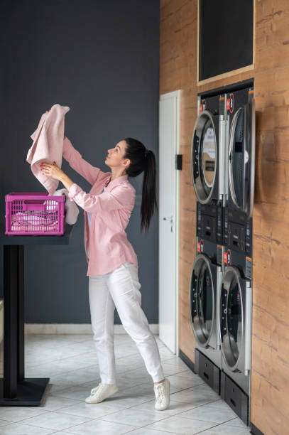 istock Young woman unloading washing machine in public laundry. 1534086882