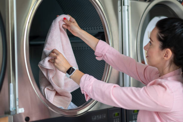 istock Young woman unloading washing machine in public laundry. 1534086883