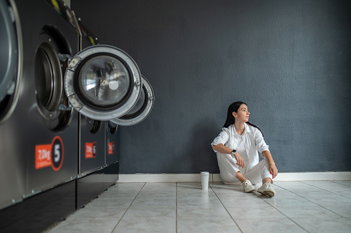Young brunette woman waiting in public laundry room.