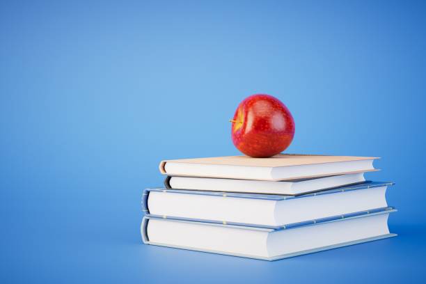 Books tower with apple isolated on blue background. 3d render