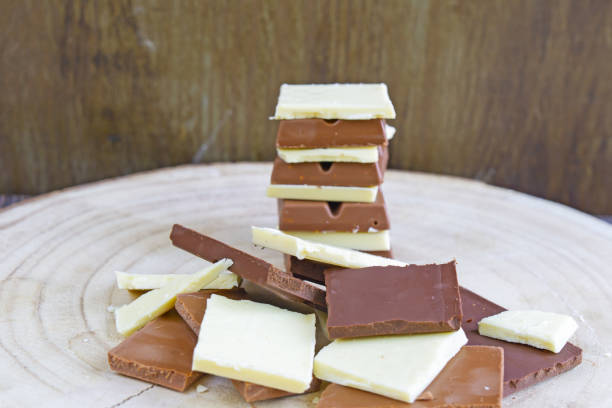 istock Dark, milk and white organic chocolate squares forming a pile and a stack on wooden background. 1534178365
