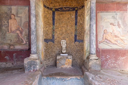 Pompeii, Naples, Italy - June 26, 2021: Ruins of ancient city destroyed by eruption of the volcano Vesuvius in 79 AD. Statue and frescoes at House of Octavius Quartio (Casa di Ottavio Quartione)