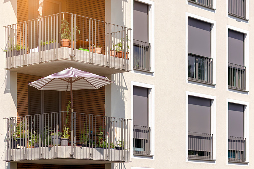 Roller Blinds on Window Outside.  Modern Facade House or Apartment Building with Sun Protection External Shutters on French Windows and Balcony.