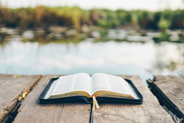 istock Open Bible on a wooden board near the river 1534215381