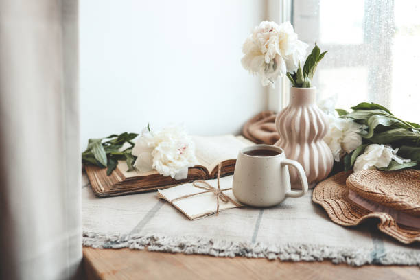 istock Cup of tea, straw hat, open book and peonies, spring still life 1534223854