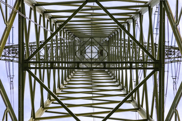 Steel beams, wires and a bird's nest in a huge power pole photographed directly from below against the sky