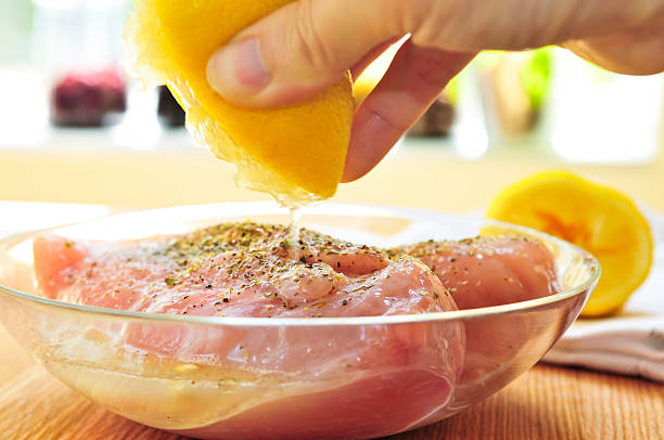 Hand marinating raw chicken breasts Marinating raw chicken breasts in lemon juice and herbs marinade stock pictures, royalty-free photos & images