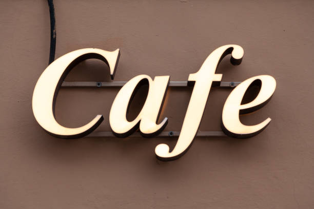 Inscription cafe in glowing white letters on wall stock photo