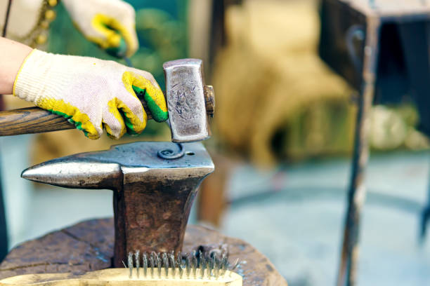 A blacksmith's hammer hits a metal billet on an anvil