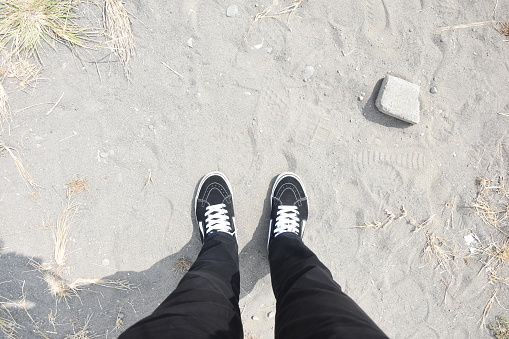 Personal perspective of sneakers and sand during the day