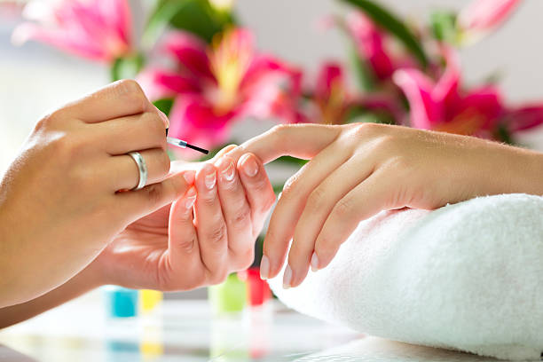 Woman in a nail salon receiving a manicure Woman in a nail salon receiving a manicure by a beautician nail salon stock pictures, royalty-free photos & images