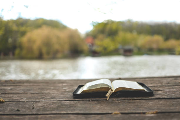 istock Open Bible on a wooden board near the river 1534277083