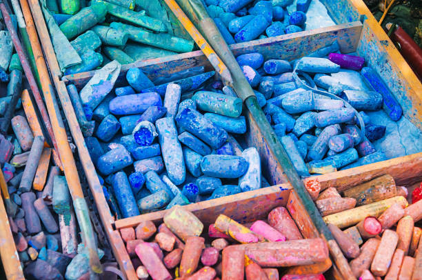 A wooden, partitioned box filled with an assortment of well used artist pastel chalks.