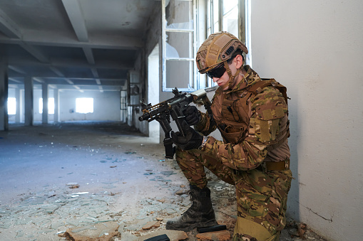 soldier in action near window changing magazine and take cover.