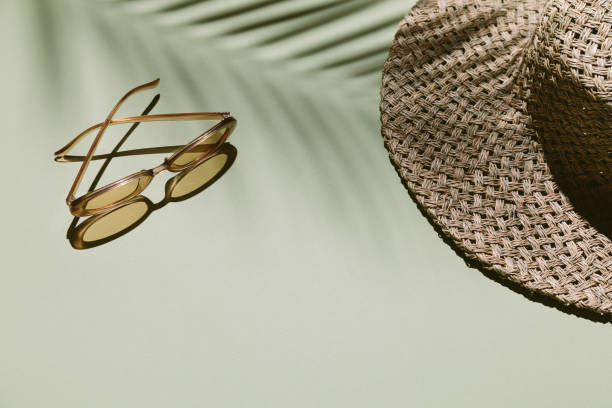 Summer flat lay with straw hat and sunglasses on green background with palm leaf shadow, sun and sunlight. Vacation, holiday, summer creative minimal concept, copy space, banner.