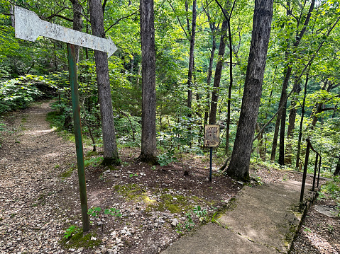 Direction sign points down a path in the lush foliage in the woods of Eureka Springs, Arkansas