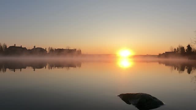 Orange sky Sunrise 4k timelapse footage. Clouds and Sun Rising Sky Time Lapse. reflection of sun in the water. Beginning of day fall season Concept. Fog morning over a pond moving toward sunlight