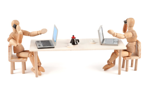 Two wooden mannequins at work. With laptops and handy. And the coffee pot. Concept for work, office, communication, coffee house and a lots of more.