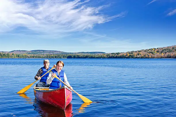 Photo of Father and daughter rowing a canoe on a calm lake