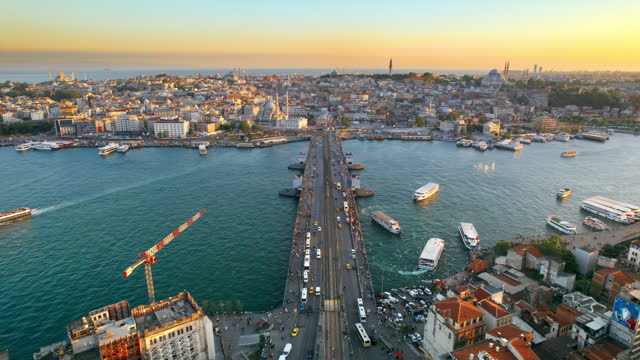 Aerial drone view of Istanbul at sunset, Turkey. Multiple residential buildings, mosques, Galata bridge over the Golden Horn waterway with multiple floating ships