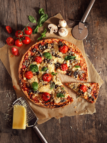 Handmade pizza with chicken, mushrooms, cheese, tomatoes and basil.