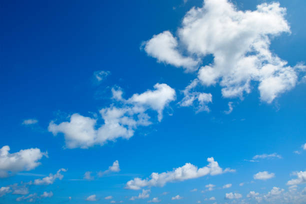istock White fluffy clouds and bright sun on blue sky. 1534452442
