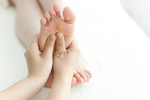 o terapeuta de beleza com mensagens relativas aos um pé - reflexology pedicure massaging human foot imagens e fotografias de stock