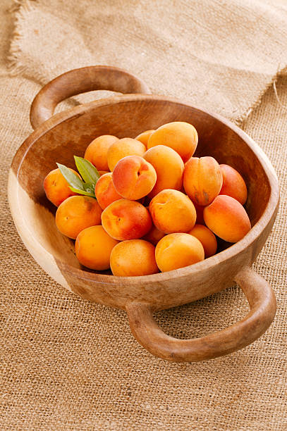 istock fresh apricots on wooden bowl, shallow DOF 153448824