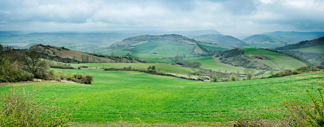 ** Stitched panorama** Scenic in Languedoc-Roussillon, France. Looking down on farmland and remote farmhouse and the distant cliffs on a moody winter day