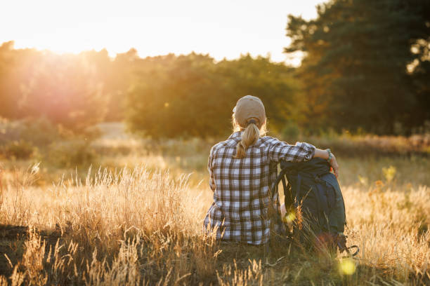 istock Woman with backpack is resting in nature and enjoying summer sunset 1534519878