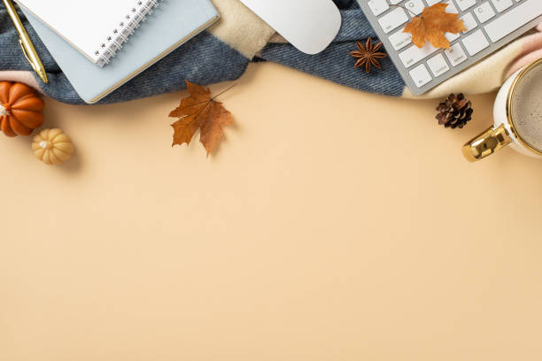 istock Autumn-themed workspace at home. Top view image of keyboard and mouse, notepad and pen, cup of coffee, scarf, pumpkin candles and maple foliage with space for promotion on grey isolated background 1534525627