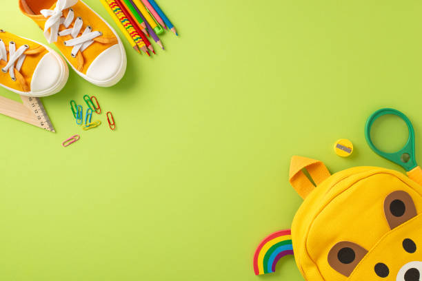 istock Prep for grade school. Top view showcasing funny bear backpack, color pencils, plasticine, ruler, clips, magnifying glass, and sneakers on pastel green backdrop with space for text or promotions 1534526579