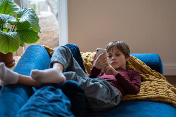 istock Depressed upset child with smartphone lying on sofa 1534531984