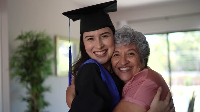 Young graduate woman embracing with grandmother at home