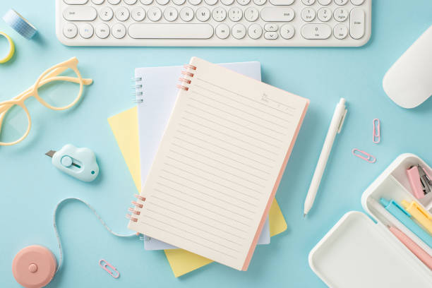 istock Top view photo of distant education workplace featuring planner with blank page and lots of school supplies, including pen, clips, tape and keyboard with mouse on isolated pastel blue backdrop 1534534080