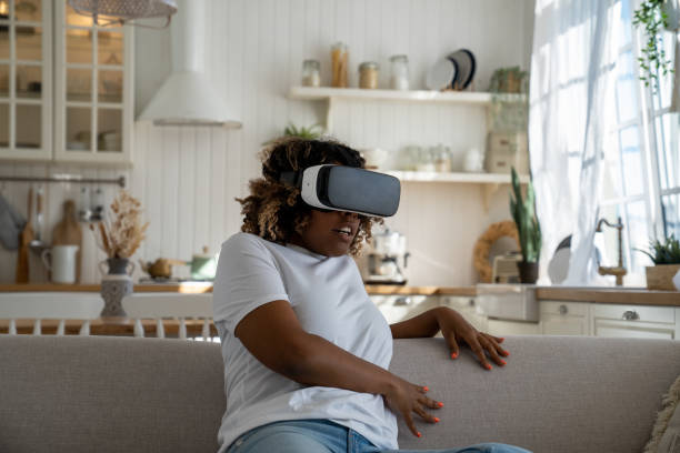 istock Shocked surprised young black woman sitting on sofa feeling scared in virtual reality 1534547294